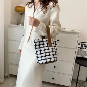 Detail of checkered tweed tote bag with premium brown leather handles and base