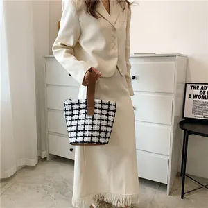 Detail of black and white checkered tweed tote bag with brown leather handle stitching