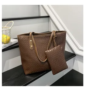 Brown woven leather tote bag with a matching small zipper pouch on a staircase