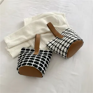 Top view of two houndstooth patterned tote bags with brown leather base and handles