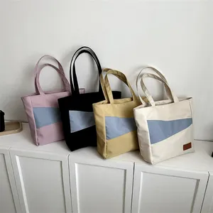 Detailansicht von vier großen Canvas-Tragetaschen in Pink, Schwarz, Gelb und Cremeweiß