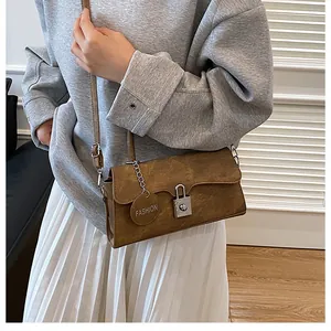 Detail of vintage brown suede crossbody bag featuring silver lock and fashion tag