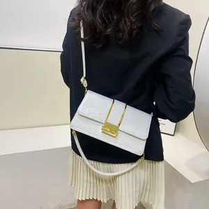 Dettaglio della borsa a tracolla bianca coccodrillo con finiture dorate su modella