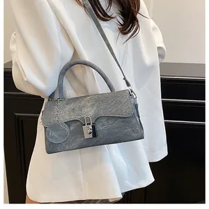 Detail of gray retro shoulder bag with silver square lock and circular fashion charm