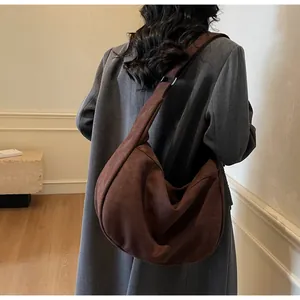 Detail of the brown suede tote bag with wide strap on a model wearing a grey wool coat