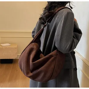 Detail of a large brown suede hobo bag on shoulder, minimalist design for daily commute