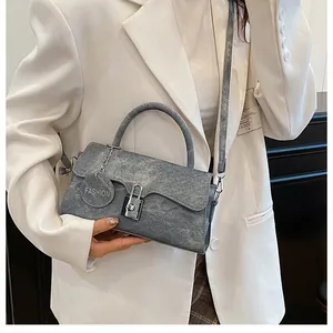 Detail of blue vintage textured shoulder bag featuring silver lock and fashion tag