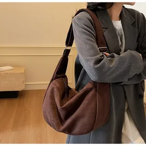 Side view of brown suede crescent hobo bag featuring adjustable shoulder strap