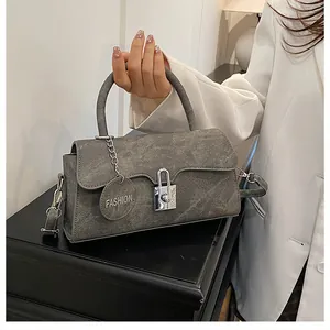 Close-up of matte grey leather bag featuring a silver metal buckle and fashion charm tag