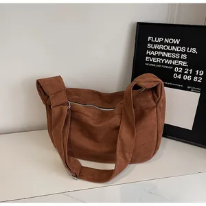Detail of caramel suede tote bag featuring silver zipper and wide adjustable strap