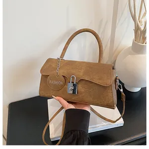 Close-up of retro brown handbag with silver metal lock and fashion tag on books