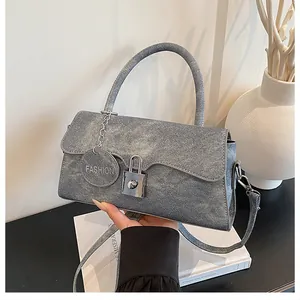 Detail view of the silver metal clasp and texture on the grey denim shoulder bag