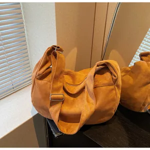 Detailed texture of suede-like orange crescent bag with silver metallic buckle on strap