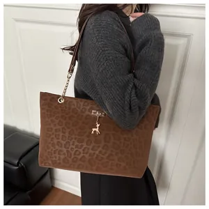 Détail du sac cabas léopard avec pendentif cerf en métal et bandoulière sur l'épaule