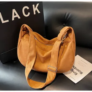 Detail of a brown corduroy tote bag on a black sofa showing soft fabric and strap