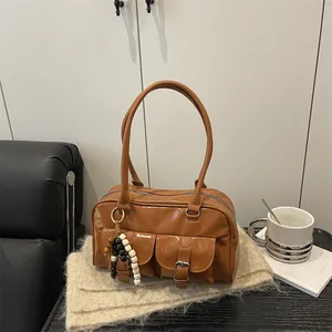 Vintage braune Boston-Tasche mit Perlenanhänger auf einem beigen Schal dekoriert