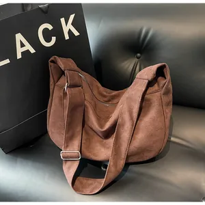 Detail of dark brown canvas half-moon crossbody bag with wide strap and silver buckle