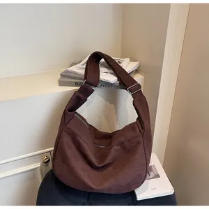 Detailed view of dark brown suede tote bag featuring silver hardware and wide shoulder strap