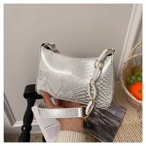 Détail du sac baguette à motif serpent avec chaîne en résine blanche et dorée