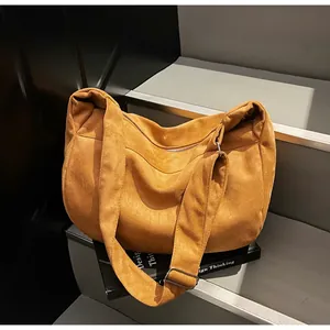 Detail of soft brown suede shoulder bag with adjustable silver buckle on a gray stone step