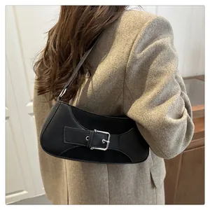 Detalle de bolso negro de piel mate con hebilla metálica y costuras de ante para mujer