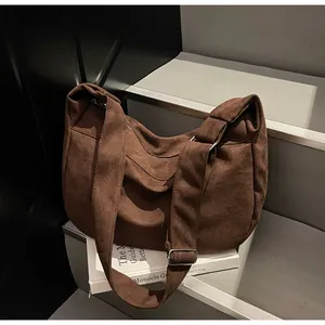 Close-up of brown canvas crescent bag with adjustable strap and silver metal buckle