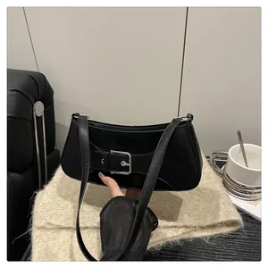 Detalle del bolso baguette de cuero negro con hebilla grande de metal plateado pulido