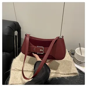 Primer plano de bolso de hombro burdeos con hebilla plateada y panel de ante