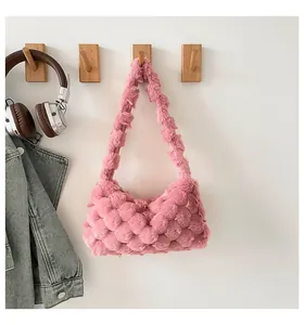 Dettaglio della borsa a tracolla peluche rosa con trama intrecciata appesa a un gancio