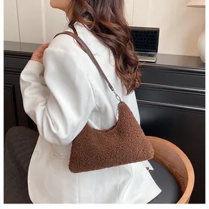 Brown faux shearling crescent shoulder bag with deep leather strap shown on model's shoulder