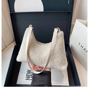 Detail of creamy white faux shearling hobo bag texture with leather strap in gift box