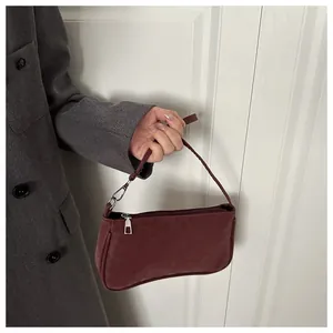 Detailed close-up of a burgundy suede baguette bag with silver hardware and fine texture