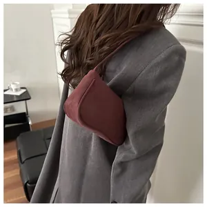 Model wearing a wine red minimalist baguette bag over the shoulder with a grey blazer