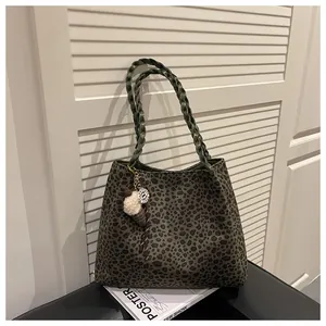 Detalle del bolso tote con estampado de leopardo verde oscuro y colgante de peluche