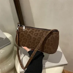 Detail of dark brown leopard print baguette bag with velvet texture and silver hardware