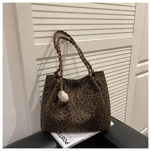 Detalle del bolso tote de leopardo con asas trenzadas marrones y colgante decorativo