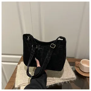 Detail of black leopard print tote bag with soft suede texture and gold metal hardware