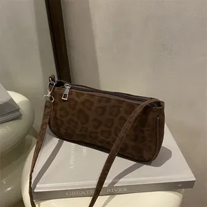 Detail of a brown leopard print baguette bag in faux suede with silver hardware accent