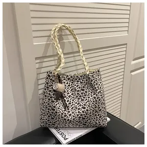 Detalle del bolso tote de leopardo con asas tejidas y colgante de helado en mesa