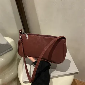 Detail of burgundy baguette bag with matte texture and silver zipper under hand-held view