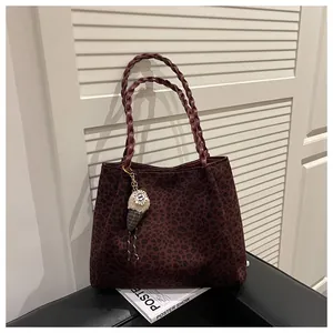 Detalle de bolso tote granate con estampado de leopardo, asas trenzadas y accesorio