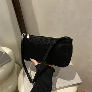 Detail of black baguette bag with leopard print texture and silver zipper closure