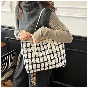 Close-up of black and white checkered tweed tote bag with beige leather handles and gold studs