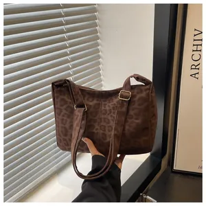 Detailed macro view of the brown leopard print pattern and matte gold buckles on the tote bag