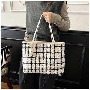 Detail of black and white striped tweed tote bag showing gold studs and shoulder strap