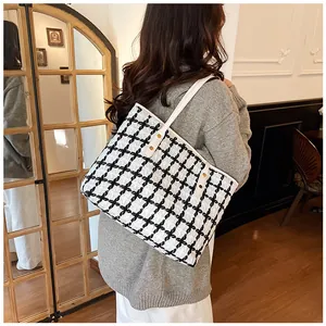 Detail of large black and white tweed tote bag with white leather strap and gold rivets