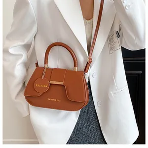 Détails d'un sac selle en cuir marron avec garniture dorée et étiquette ronde logo