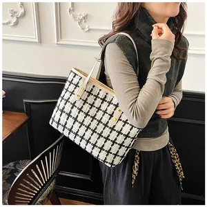 Close-up of black and white checkered tweed tote bag with premium cream leather strap