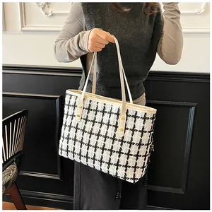 Detail view of tweed tote bag showing black and white check pattern and golden rivet studs