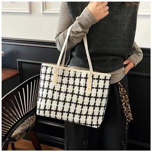 Detail shot of black and white tweed tote bag showing striped pattern and gold hardware